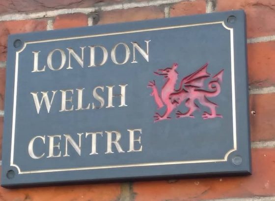 Sign reading 'London Welsh Centre' on a brick wall, with a Red Dragon on it